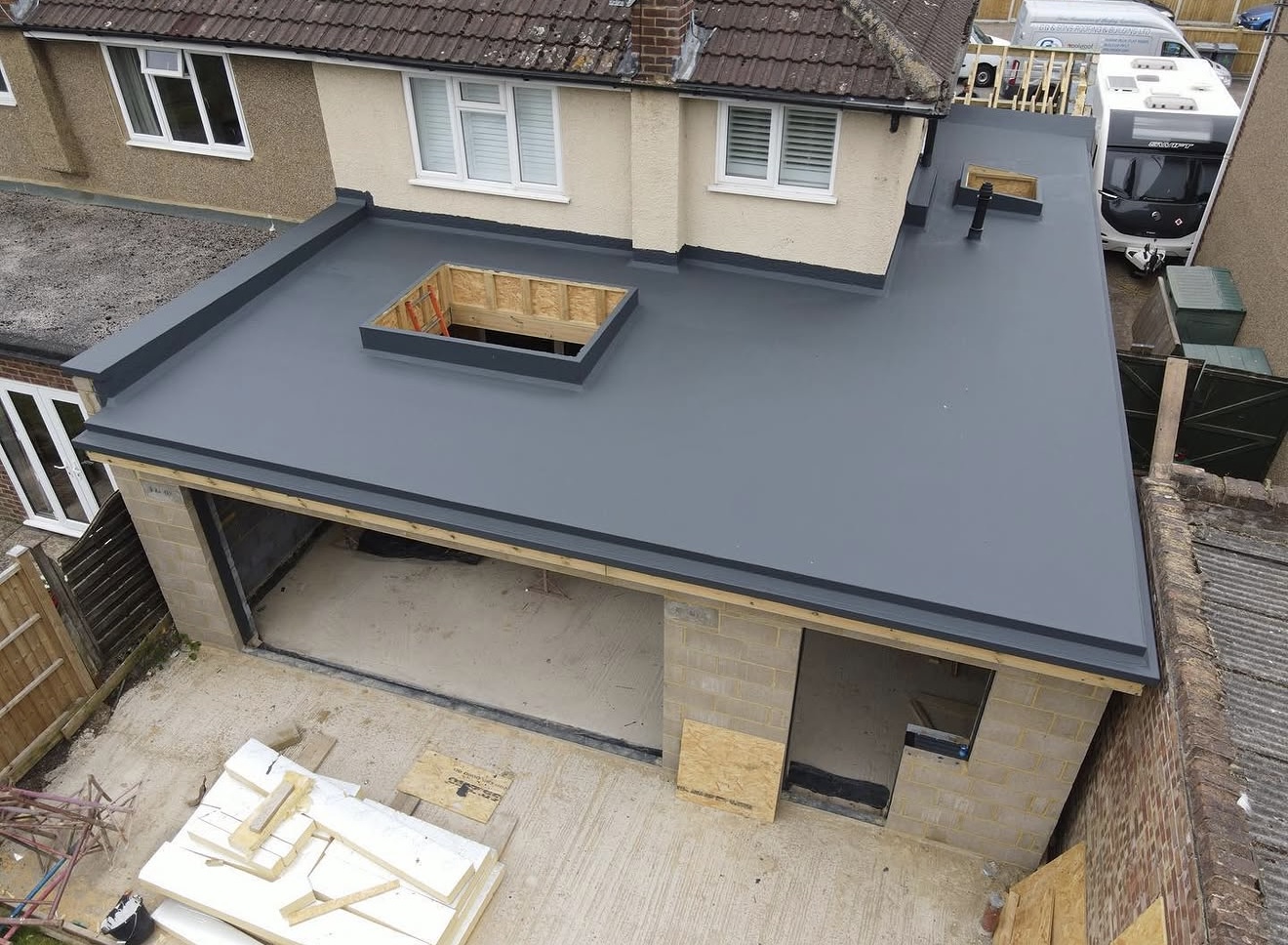 Grey flat roof installation on a garage extension, viewed from the neighbouring roof